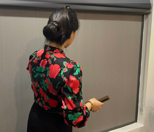 Rèm tổ ong cửa sổ với người đang thao tác thanh kéo